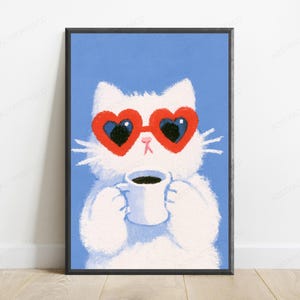 May include: A framed wall art print featuring a fluffy white cat against a solid blue background. The cat wears large red heart-shaped sunglasses and holds a white mug filled with dark coffee. The illustration has a textured, painterly style.