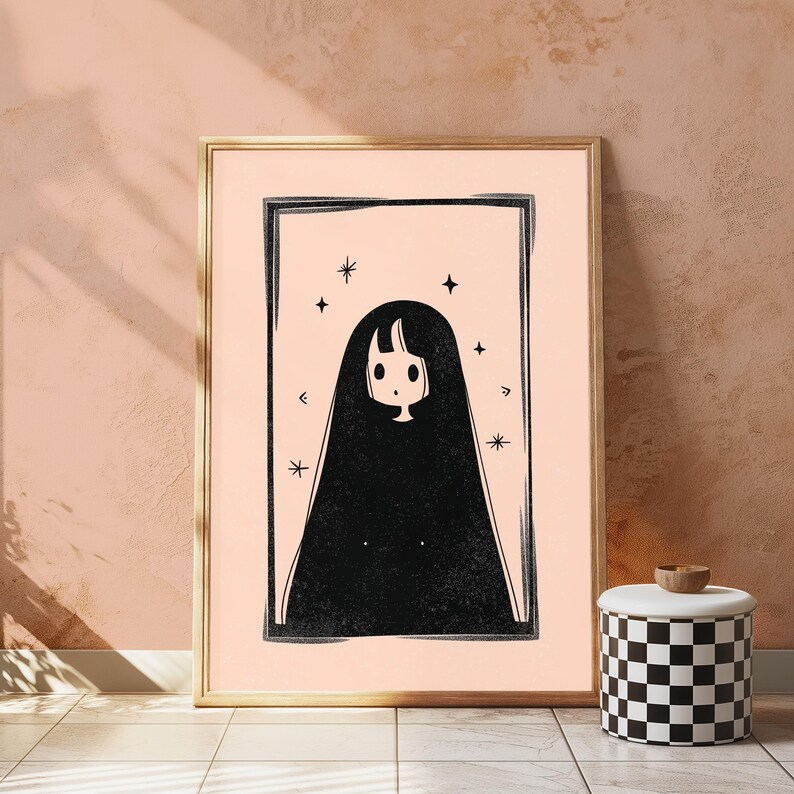 Peut inclure: Une impression d'art encadr&eacute;e repr&eacute;sentant une illustration en noir et blanc d'un personnage aux longs cheveux noirs et au petit visage, centr&eacute; dans un cadre rectangulaire sur fond p&ecirc;che clair, agr&eacute;ment&eacute; de plusieurs petites &eacute;toiles &agrave; quatre branches.