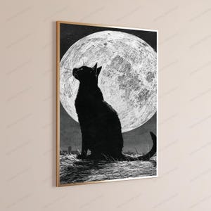 May include: A rectangular wall art print in a thin gold frame featuring a black silhouette of a cat sitting in a field of grass. The cat is looking up toward a large, textured white full moon set against a dark, starry night sky background.