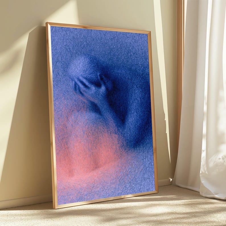 May include: A framed vertical wall art print featuring a textured, blue, abstract human figure with hands covering the face. The figure is composed of dense, scribbled lines, transitioning into a soft, glowing pink hue at the lower section.