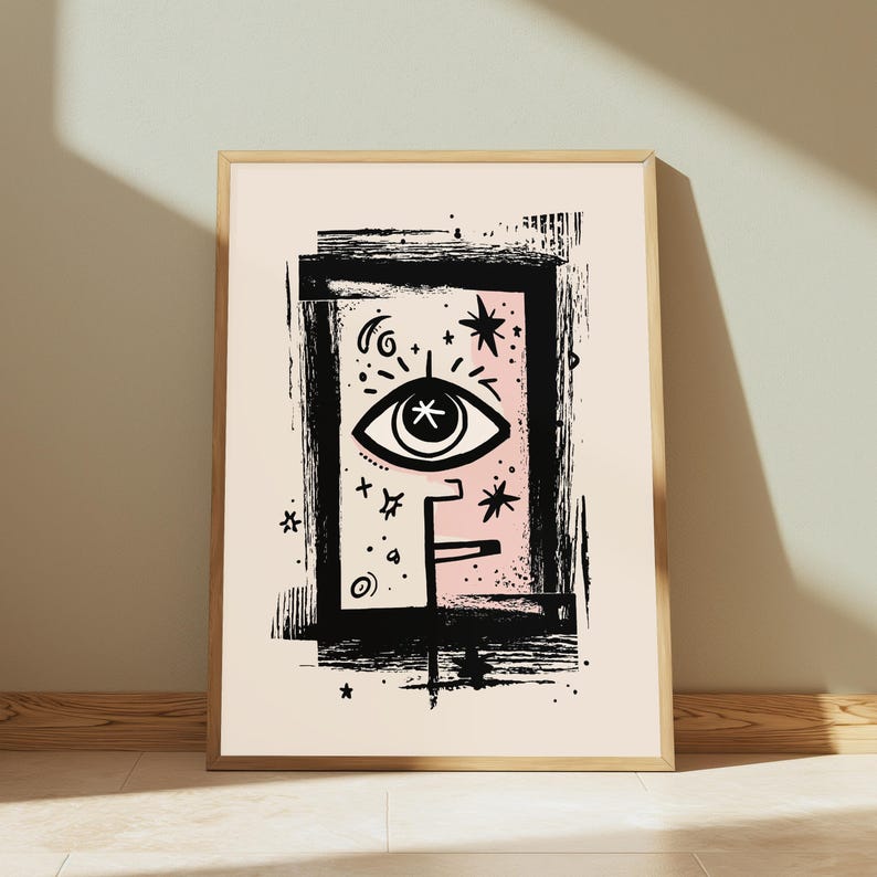 Peut inclure: Une affiche d'art encadr&eacute;e pr&eacute;sentant une illustration &agrave; l'encre noire d'un &oelig;il stylis&eacute; centr&eacute; dans un cadre rectangulaire. Le motif inclut des &eacute;l&eacute;ments c&eacute;lestes comme des &eacute;toiles et des croissants sur un fond rose p&acirc;le, le tout sur papier cr&egrave;me.