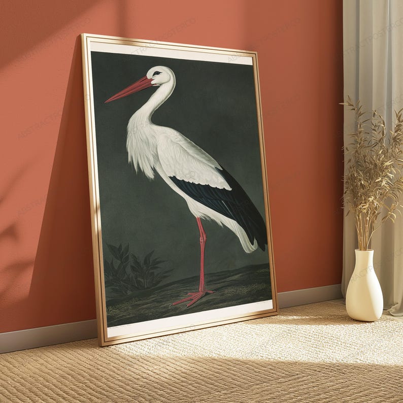 May include: A framed vertical wall art print featuring a detailed illustration of a white stork with black wing feathers, a long red beak, and red legs, standing against a dark, muted green background with subtle foliage at the base.