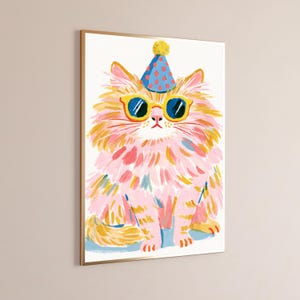 K&ouml;nnte beinhalten: Ein gerahmter Wandkunstdruck, der eine flauschige Katze mit langem rosa und gelbem Fell zeigt. Die Katze tr&auml;gt einen blauen Partyhut mit roten Punkten und eine Sonnenbrille mit gelbem Rand. Die Illustration zeigt sichtbare Pinselstriche.