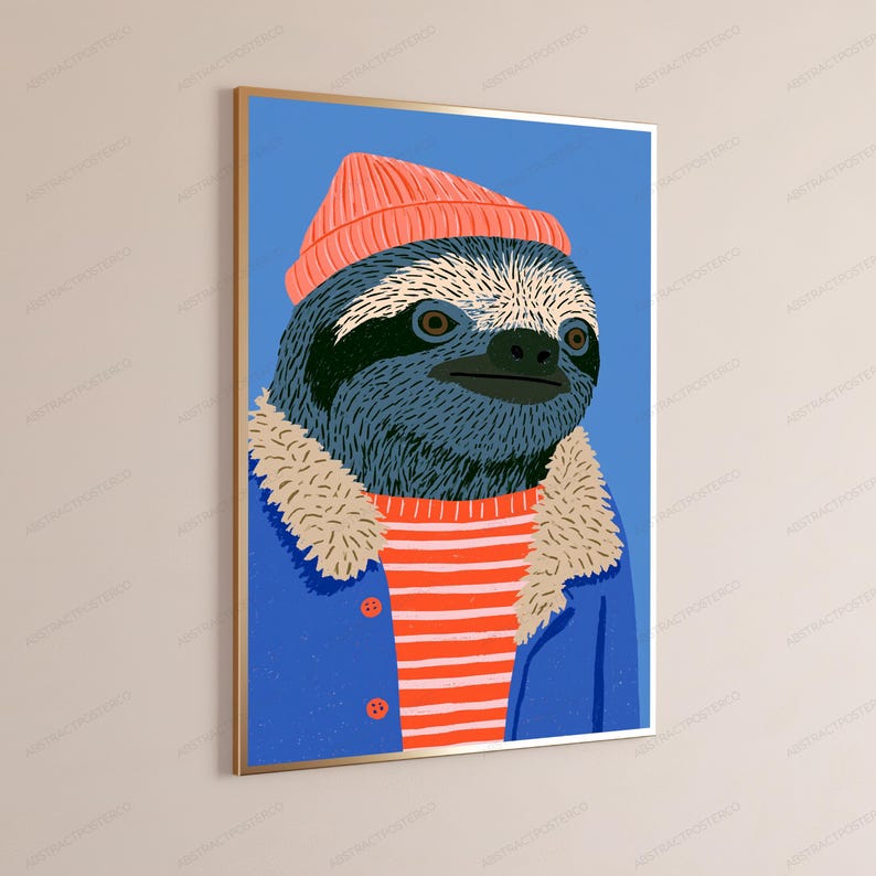 May include: A framed wall art print featuring a stylized illustration of a sloth wearing a coral-colored beanie, a red and white striped shirt, and a blue jacket with a beige faux-fur collar, set against a solid blue background.