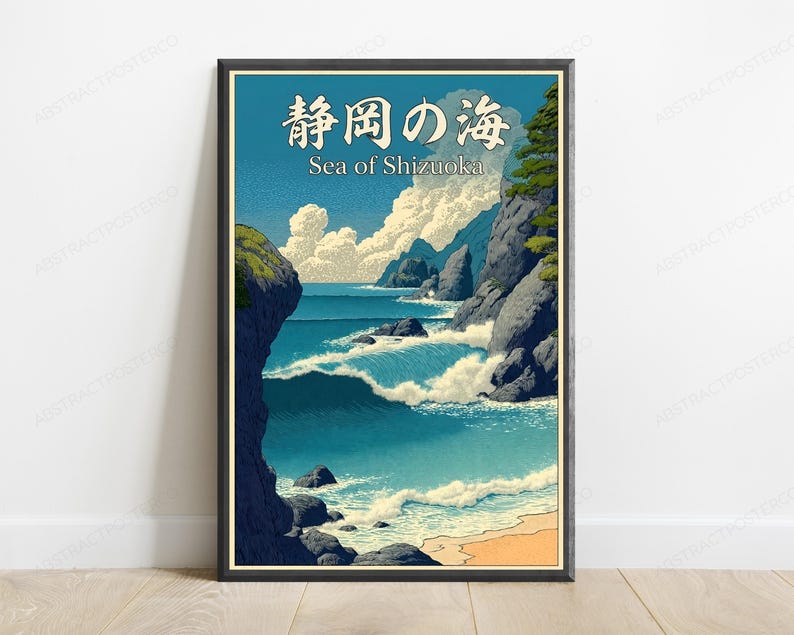 Puede incluir: Una impresi&oacute;n art&iacute;stica enmarcada que muestra un paisaje costero con olas azules rompiendo contra acantilados rocosos oscuros, una playa de arena y nubes blancas en un cielo azul. El texto en la parte superior dice 静岡の海 y Sea of Shizuoka.