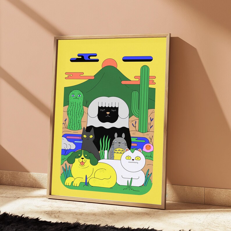 May include: A framed art print featuring a yellow background with a green mountain, a red sun, and a desert landscape. The illustration depicts a black sheep, a black cat, a grey creature, a yellow dog, and a white cat among cacti and blue water.