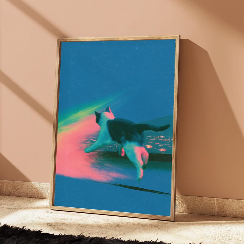 May include: A framed vertical art print featuring a black and white cat leaping through a vibrant blue space. A glowing pink and yellow light trail follows the cat, which is positioned above a distant, blurred city skyline under a dark blue sky.