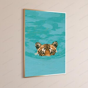 May include: A framed wall art print featuring an oil painting style depiction of a tiger head emerging from vibrant turquoise water. The tiger has orange fur with black stripes and is positioned in the centre of the textured blue water surface.