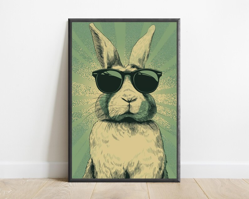May include: A framed wall art print featuring a stylized illustration of a rabbit wearing black sunglasses. The rabbit is centered against a light green background with a radiating sunburst pattern in a darker shade of green and cream.