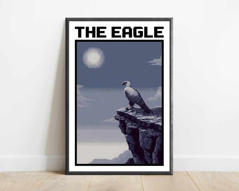 May include: A framed pixel art print titled THE EAGLE, featuring a white and grey eagle perched on a dark rocky cliff overlooking a misty landscape under a pale moon. The artwork uses a limited colour palette of blues, greys, and whites.