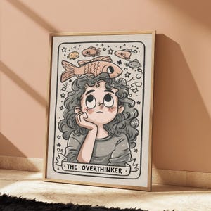 May include: A framed wall art print featuring a cartoon illustration of a person with curly hair resting their chin on a hand. Above the person, several small fish and stars are drawn. The text THE OVERTHINKER is printed at the bottom.