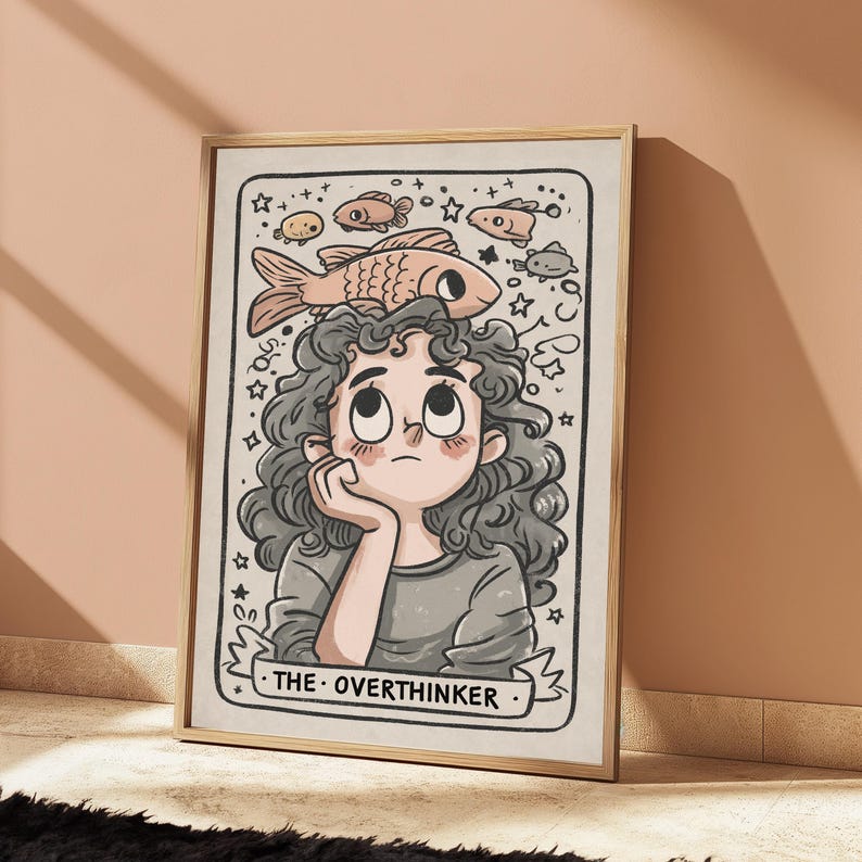 May include: A framed wall art print featuring a cartoon illustration of a person with curly hair resting their chin on a hand. Above the person, several small fish and stars are drawn. The text THE OVERTHINKER is printed at the bottom.