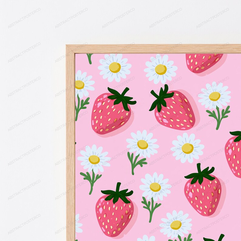 May include: A framed wall art print featuring a repeating pattern of pink strawberries with green stems and white daisies with yellow centers on a light pink background. The print is enclosed in a simple, light-colored wooden frame.