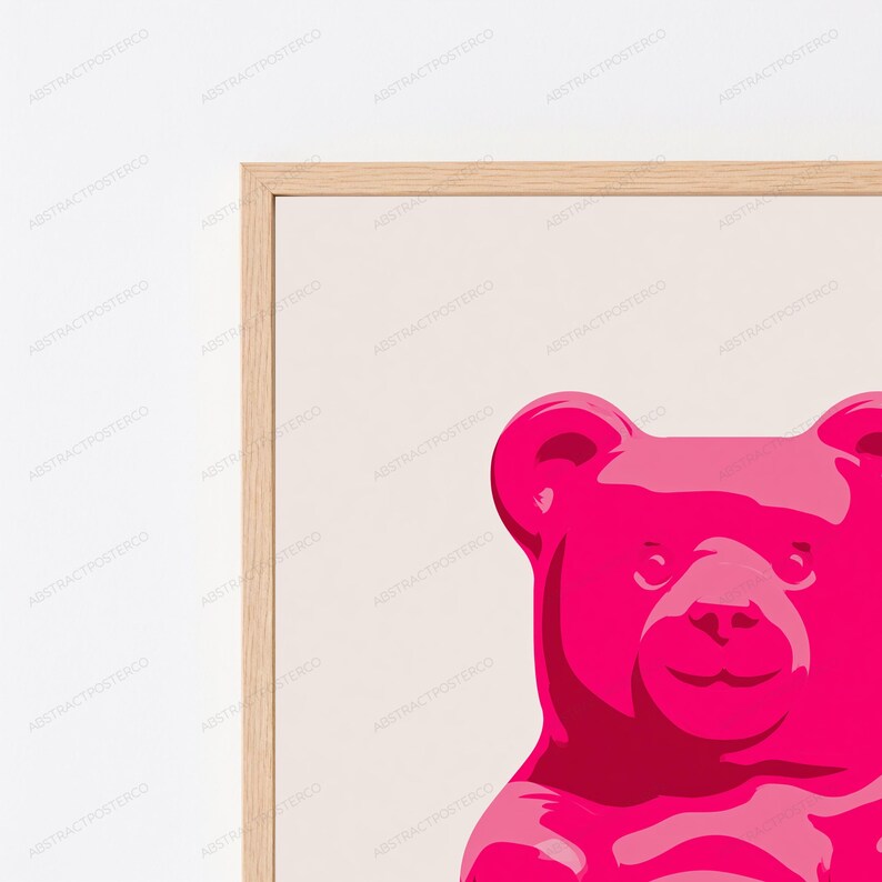 May include: A framed wall art print featuring a vibrant hot pink gummy bear illustration centered on a light beige background. The artwork is enclosed in a light-toned wooden frame, showcasing a clean, graphic design with bold color contrast.