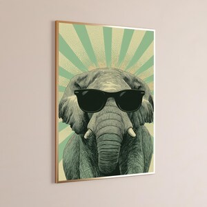 May include: A rectangular wall art print featuring a detailed illustration of a grey elephant wearing black sunglasses. The background consists of a light green and cream-coloured sunburst pattern with a dotted texture throughout the design.