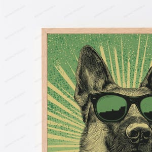 May include: A framed wall art print featuring a detailed black and white illustration of a German Shepherd dog wearing dark green sunglasses. The background is a vibrant green with a radiating sunburst pattern and a speckled texture effect.