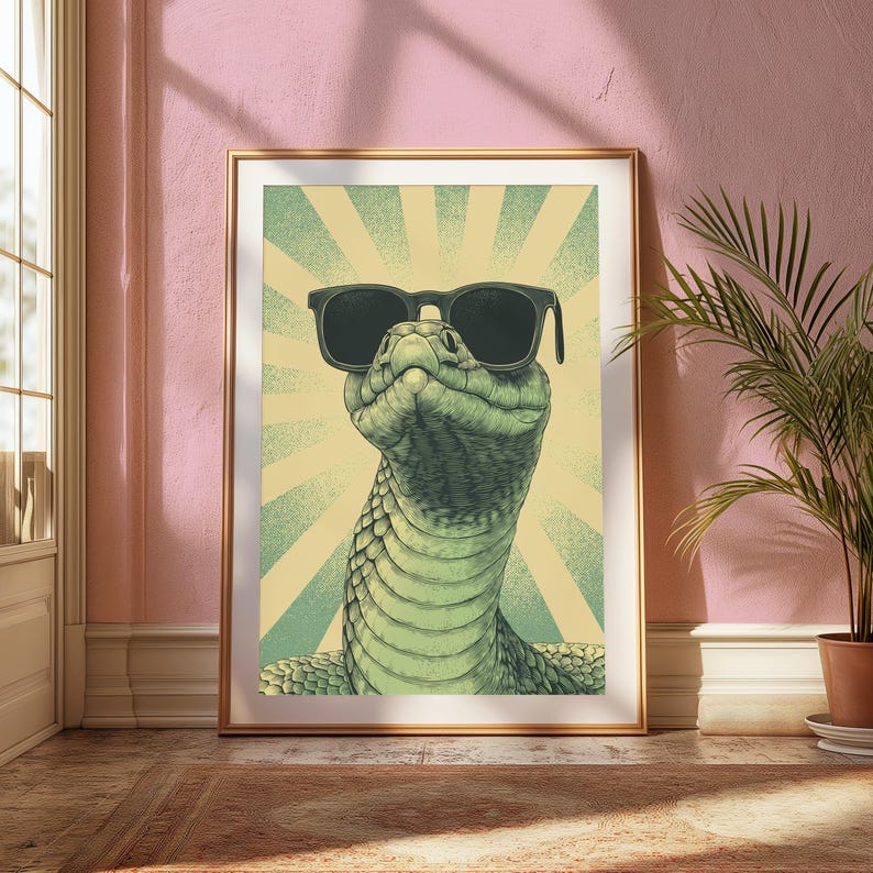 May include: A framed wall art print featuring a detailed illustration of a green snake wearing black sunglasses. The snake is positioned centrally against a background of light yellow and green radiating sunburst lines in a vintage graphic style.