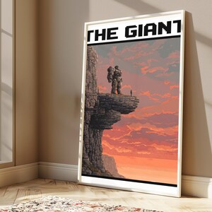 May include: A framed vertical poster featuring pixel art of a large stone figure standing on a cliff edge next to a small person. The sky is a gradient of orange and pink clouds. The text THE GIANT is printed in black block letters at the top.