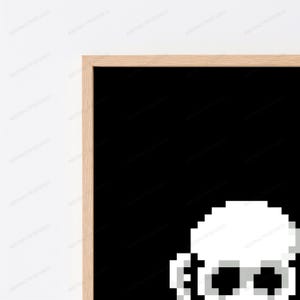 May include: A framed wall art piece featuring a pixelated white skull graphic set against a solid black background. The artwork is enclosed in a light-toned wooden frame with a clean, straight-edged profile, showcasing a high-contrast design.