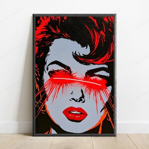 May include: A rectangular framed wall art print featuring a stylized graphic illustration of a face in shades of gray, black, and vibrant red. The subject has bright red hair and red lips, with intense red light beams emanating from the eyes.