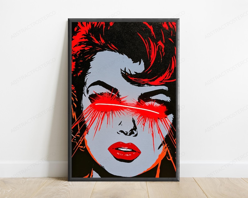 May include: A rectangular framed wall art print featuring a stylized graphic illustration of a face in shades of gray, black, and vibrant red. The subject has bright red hair and red lips, with intense red light beams emanating from the eyes.
