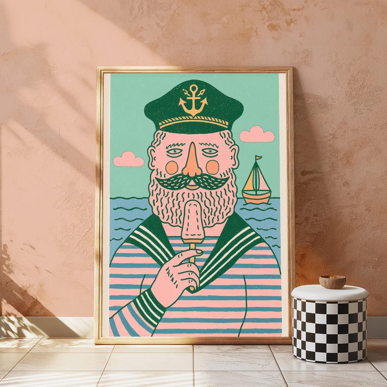 K&ouml;nnte beinhalten: Ein gerahmter Kunstdruck zeigt einen b&auml;rtigen Seemann mit einer dunkelgr&uuml;nen Kapit&auml;nsm&uuml;tze mit goldenem Ankeremblem und einem rosa-blau gestreiften Hemd. Der Seemann isst ein Eis vor einem hellgr&uuml;nen Hintergrund mit einem kleinen Segelboot.