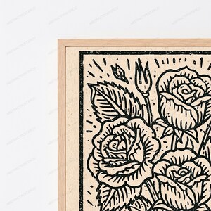 K&ouml;nnte beinhalten: Ein gerahmter Wandkunstdruck mit einer schwarzen Tuscheillustration von mehreren Rosen und Bl&auml;ttern auf hellbeigem Hintergrund. Das Kunstwerk zeigt einen kr&auml;ftigen, texturierten Linienstil mit einem dicken schwarzen Rand in einem hellen Holzrahmen.