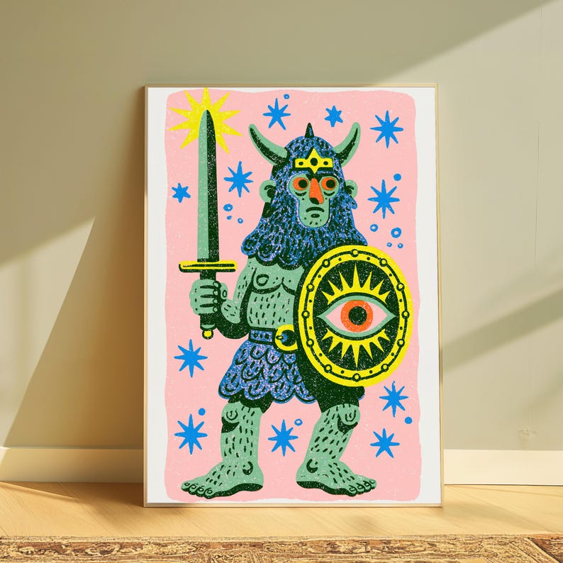 May include: A rectangular art print featuring a stylised illustration of a horned warrior figure in blue and green, holding a sword and a shield with an eye motif. The background is light pink with scattered blue stars and a yellow sunburst.