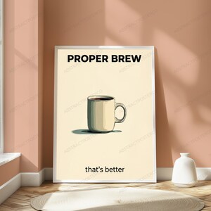 May include: A vertical rectangular poster in a white frame featuring a cream-colored background. Centered is a beige coffee mug filled with dark liquid. The text PROPER BREW appears in black at the top, and that's better is printed in black below.