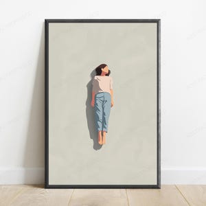 May include: A framed wall art print featuring a minimalist illustration of a figure lying flat on a light beige background. The figure wears a pale pink short-sleeved shirt and light blue trousers, with a dark shadow cast to the left side.
