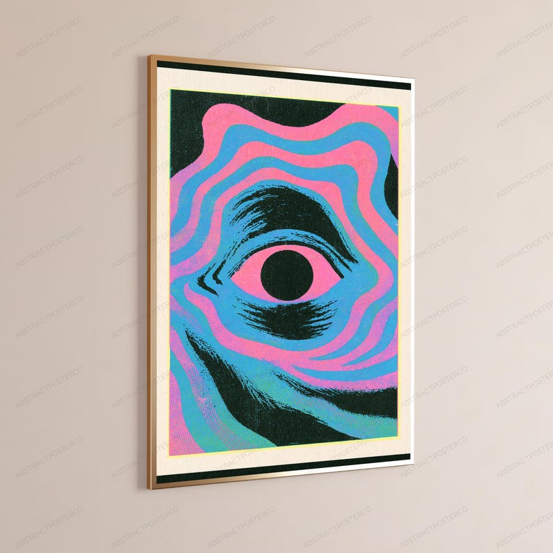 May include: A rectangular wall art print in a gold frame featuring a central black pupil surrounded by a pink iris. The eye is set against a background of wavy, concentric lines in alternating shades of bright pink, light blue, and dark teal.