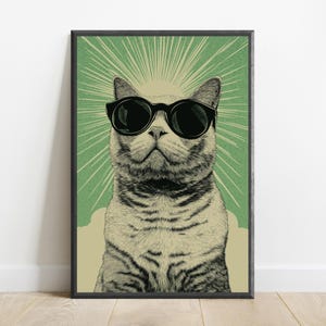 Puede incluir: Una l&aacute;mina de arte enmarcada con la ilustraci&oacute;n detallada de un gato que lleva puestas unas gafas de sol negras grandes. El gato est&aacute; centrado sobre un fondo verde con l&iacute;neas de luz radiantes que emanan detr&aacute;s de su cabeza, en un marco negro.