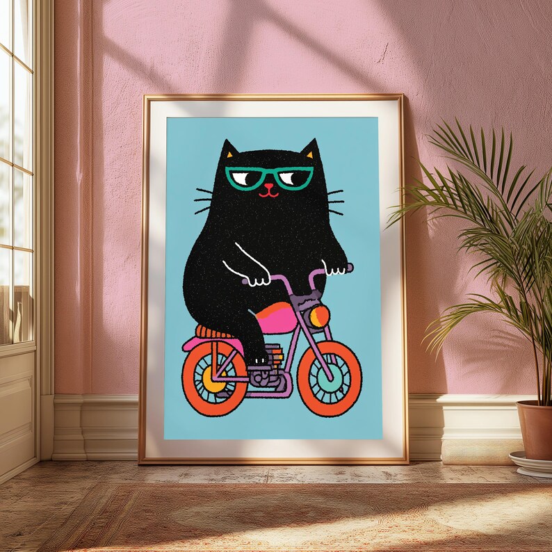 K&ouml;nnte beinhalten: Ein gerahmter Kunstdruck, der eine schwarze Katze mit t&uuml;rkisfarbener Brille auf einem lila Motorrad mit orangefarbenen R&auml;dern und einem pinken Sitz zeigt. Die Katze ist vor einem hellblauen Hintergrund in einem flachen Grafikstil dargestellt.