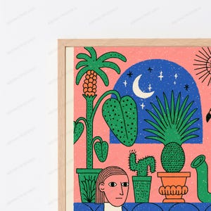May include: A framed wall art print featuring a pink background with various potted plants, including a palm and a cactus. A blue archway displays a crescent moon and stars. A stylized human face is visible at the bottom center of the illustration.