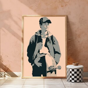 May include: A framed digital illustration featuring a person wearing a baseball cap and a hooded jacket, standing while holding a skateboard. The artwork uses a palette of muted gray tones against a solid light peach background, creating a clean graphic style.