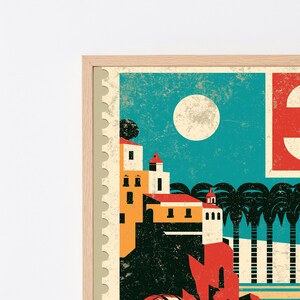 May include: A framed wall art print featuring a stylized postage stamp design. The illustration depicts a coastal scene with yellow buildings, a large white moon in a teal sky, and black palm trees, all set within a light wood frame border.