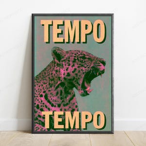 May include: A framed wall art print featuring a stylized leopard with pink and black halftone dot patterns against a muted teal background. The word TEMPO is printed in large, bold, light orange capital letters at both the top and bottom.