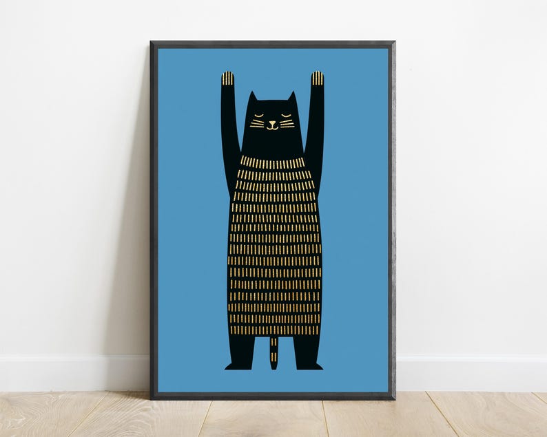 Op de afbeelding: Een ingelijste kunstprint met een zwarte kat met de voorpoten omhoog. De kat heeft gesloten ogen en een lichaam met verticale gouden lijnen tegen een effen blauwe achtergrond, geplaatst in een dunne zwarte lijst.