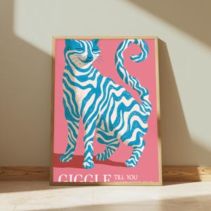 May include: A framed wall art print featuring a cat with blue and white wavy stripes against a solid pink background. The cat is standing with its tail curled upwards. The text at the bottom reads GIGGLE TILL YOU WIGGLE in white capital letters.