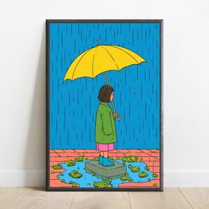 K&ouml;nnte beinhalten: Ein gerahmter Kunstdruck mit einer Cartoon-Illustration einer Person mit braunen Haaren, die w&auml;hrend eines Regenschauers auf einem Stein in einer Pf&uuml;tze steht. Die Person tr&auml;gt einen gr&uuml;nen Mantel, einen rosa Rock und blaue Stiefel unter einem gelben Regenschirm.