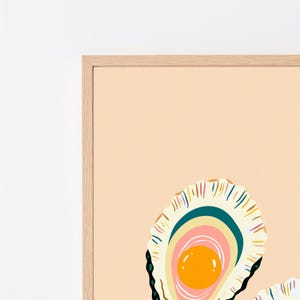 K&ouml;nnte beinhalten: Ein gerahmter Kunstdruck mit einer stilisierten Illustration einer ge&ouml;ffneten Austernschale auf hellpfirsichfarbenem Hintergrund. Das Innere der Schale zeigt konzentrische Schichten in Creme, Petrol und Rosa mit einer leuchtend orangen Perle.