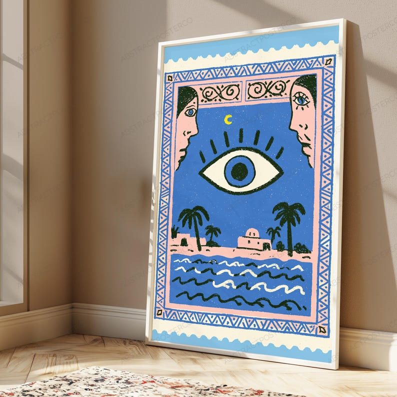 May include: A rectangular wall art print featuring a blue central panel with a large eye, a yellow crescent moon, and two faces in profile. The scene includes palm trees, a building, and wavy water, all enclosed in a pink and blue patterned border.