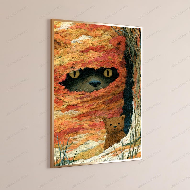 May include: A rectangular wall art print in a thin gold frame featuring a textured orange and yellow hooded creature with large yellow eyes peering out from a dark opening, with a small brown bear-like figure standing in the foreground.