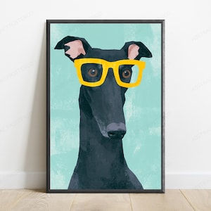 K&ouml;nnte beinhalten: Ein gerahmter Wandkunstdruck mit einer stilisierten Illustration eines schwarzen Windhundes, der eine leuchtend gelbe Brille tr&auml;gt. Der Hund ist vor einem einfarbigen, hellen t&uuml;rkisfarbenen Hintergrund dargestellt, wobei das dunkle Fell hervorsticht.