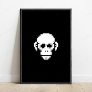May include: A framed wall art print featuring a white pixel art monkey head centered on a solid black background. The monkey design is composed of square blocks in shades of white and light gray, creating a retro digital aesthetic within a thin black frame.