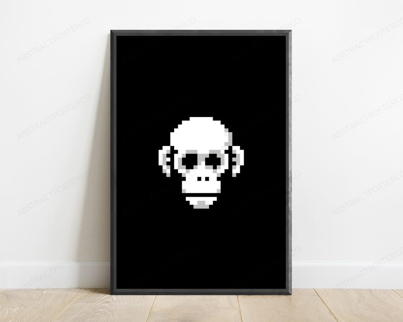 May include: A framed wall art print featuring a white pixel art monkey head centered on a solid black background. The monkey design is composed of square blocks in shades of white and light gray, creating a retro digital aesthetic within a thin black frame.