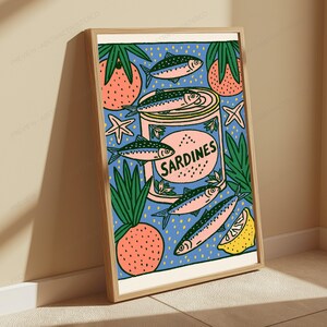 Pode incluir: Uma impress&atilde;o art&iacute;stica retangular emoldurada apresentando uma lata central com o r&oacute;tulo SARDINES, rodeada por ilustra&ccedil;&otilde;es de peixes cor-de-rosa e azuis, frutos cor de laranja com folhas verdes, fatias de lim&atilde;o amarelo e pequenas estrelas-do-mar.