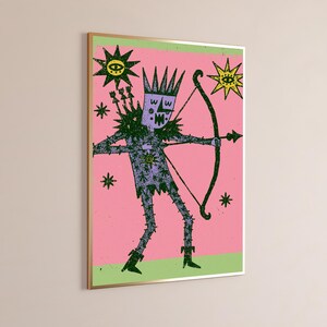 K&ouml;nnte beinhalten: Ein gerahmter Wandkunstdruck mit einer violetten, gekr&ouml;nten Figur, die einen Pfeil und Bogen vor einem rosa Hintergrund h&auml;lt. Die Figur ist mit schwarzen Sternmustern verziert und von gelben und schwarzen sonnenartigen Symbolen umgeben.