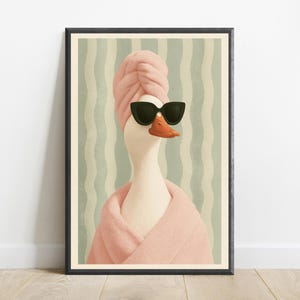 Puede incluir: Una l&aacute;mina art&iacute;stica enmarcada que muestra a un ganso blanco con una toalla rosa envuelta en la cabeza, un albornoz rosa a juego y gafas de sol negras de ojo de gato sobre un fondo de rayas verticales onduladas en tonos verde claro y crema.