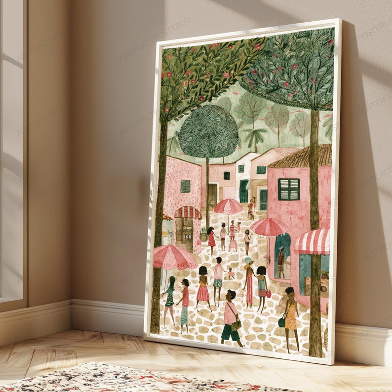 May include: A framed art print depicting a cobblestone street scene with pink buildings, green trees, and people walking under pink and white striped umbrellas. The illustration features a soft colour palette with various figures in casual clothing.